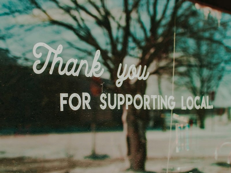 A storefront sign thanking customers for supporting local businesses